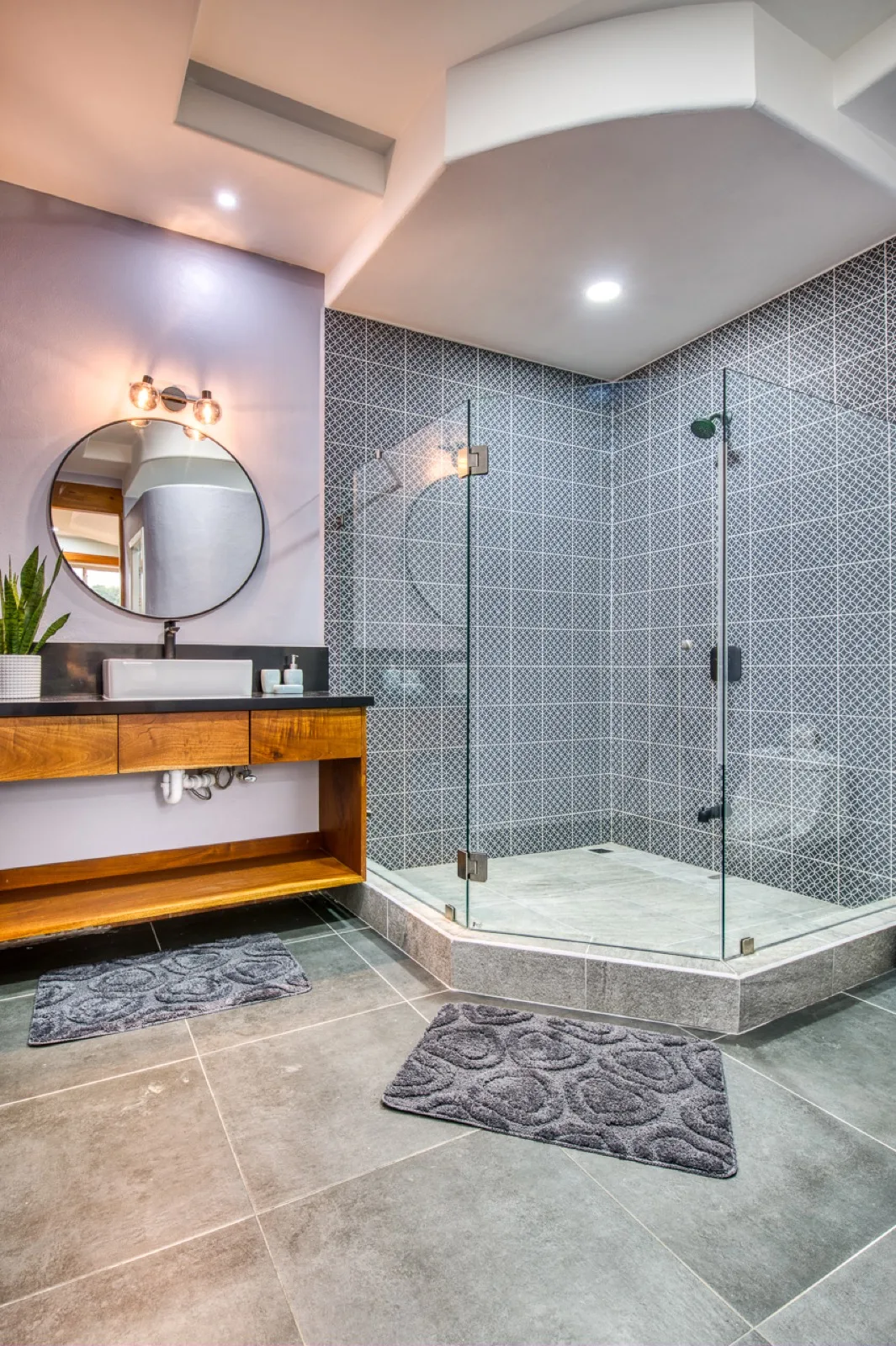 Rooftop villa bathroom with round mirror and glass shower